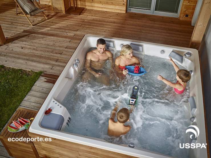 USSPA modelo COLUMBA, acabado White Pearl con mueble auxiliar Foto de jacuzzi COLUMBA exterior en el porche de madera con la familia disfrutando en su interior