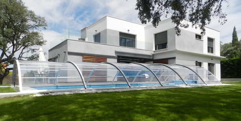 Cubierta baja fija totalmente transparente en la piscina del jardín de este moderno chalet