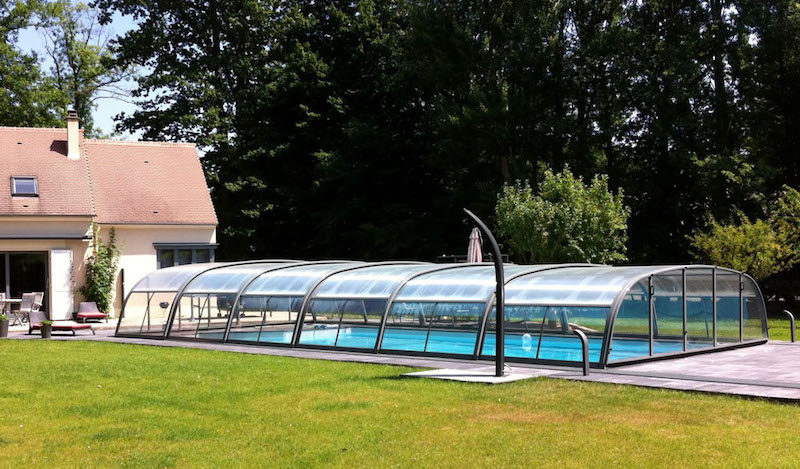 Cubierta para piscina semialta en posición cerrada protegida del viento por una fila de chopos en el lindero de la finca
