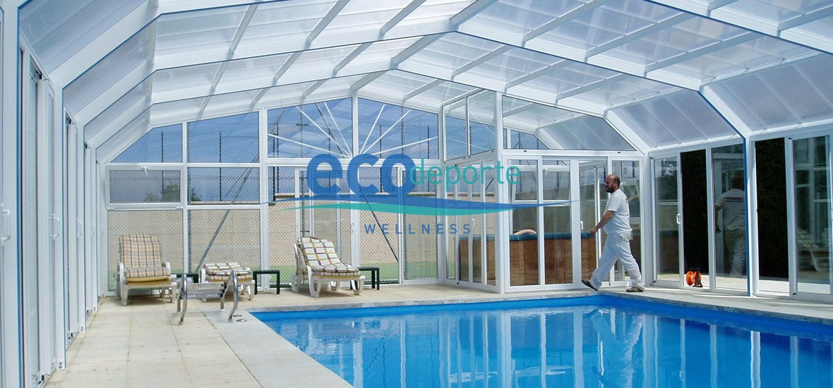 Piscina y jacuzzi dentro de este cerramiento acristalado de gran altura interior. Interior de una piscina climatizada en Madrid con una cubierta alta.