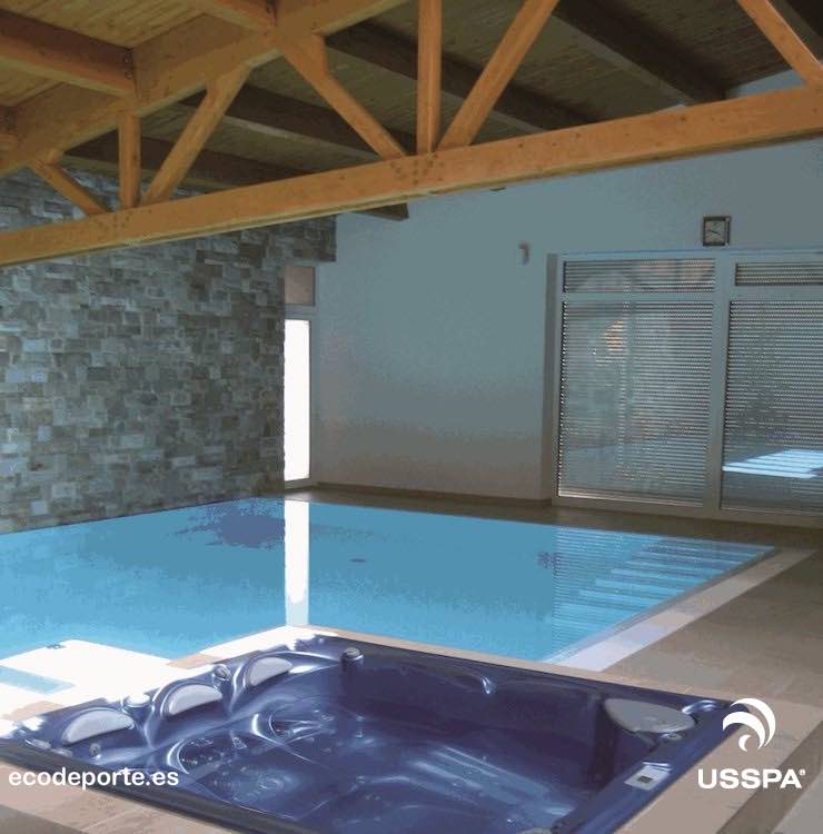 Armonía entre madera, piedra y agua Foto de jacuzzi interior elevado PERSEA al lado de piscina climatizada