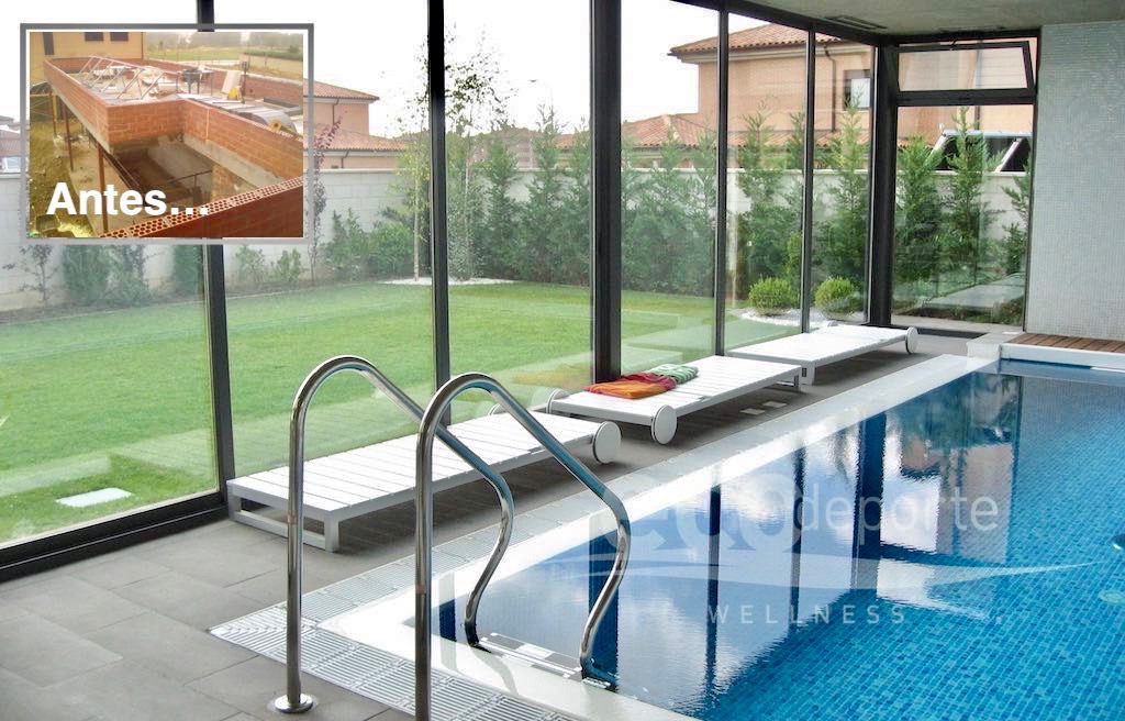Panorámica de un jardín desde el interior de la piscina desbordante cerrada con acristalamiento deslizante. Agua cristalina hasta el borde y climatización integral para nadar todo el año.
