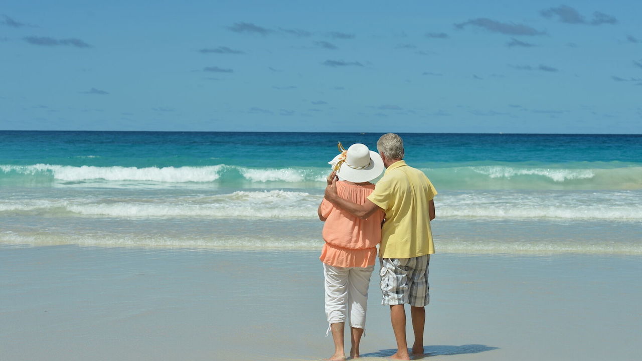 Sin riesgo en las playas con distanciamiento social Pareja de seniors abrazados mirando al mar desde la playa