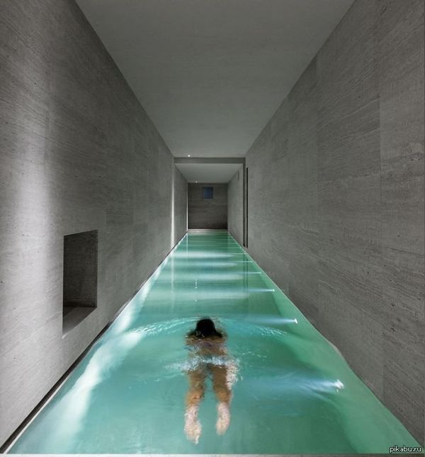 Espacios de uso privado individual. Mujer nadando en una piscina spa interior estrecha y larga