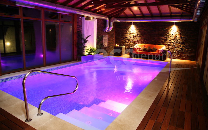 El color morado se refleja en el techo de madera y en la piedra natural. Cromoterapia color morado en el interior de la cubierta de piscina.